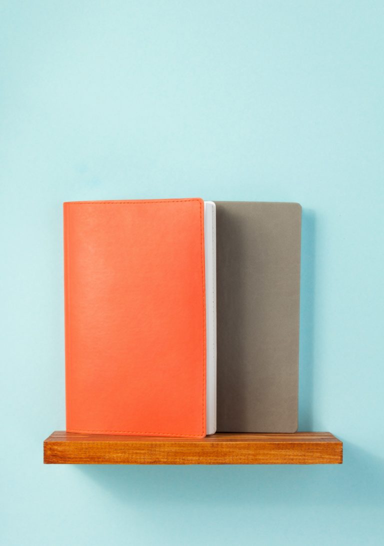notepad and book on shelf at wall background