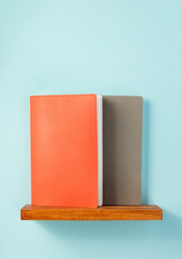 notepad and book on shelf at wall background